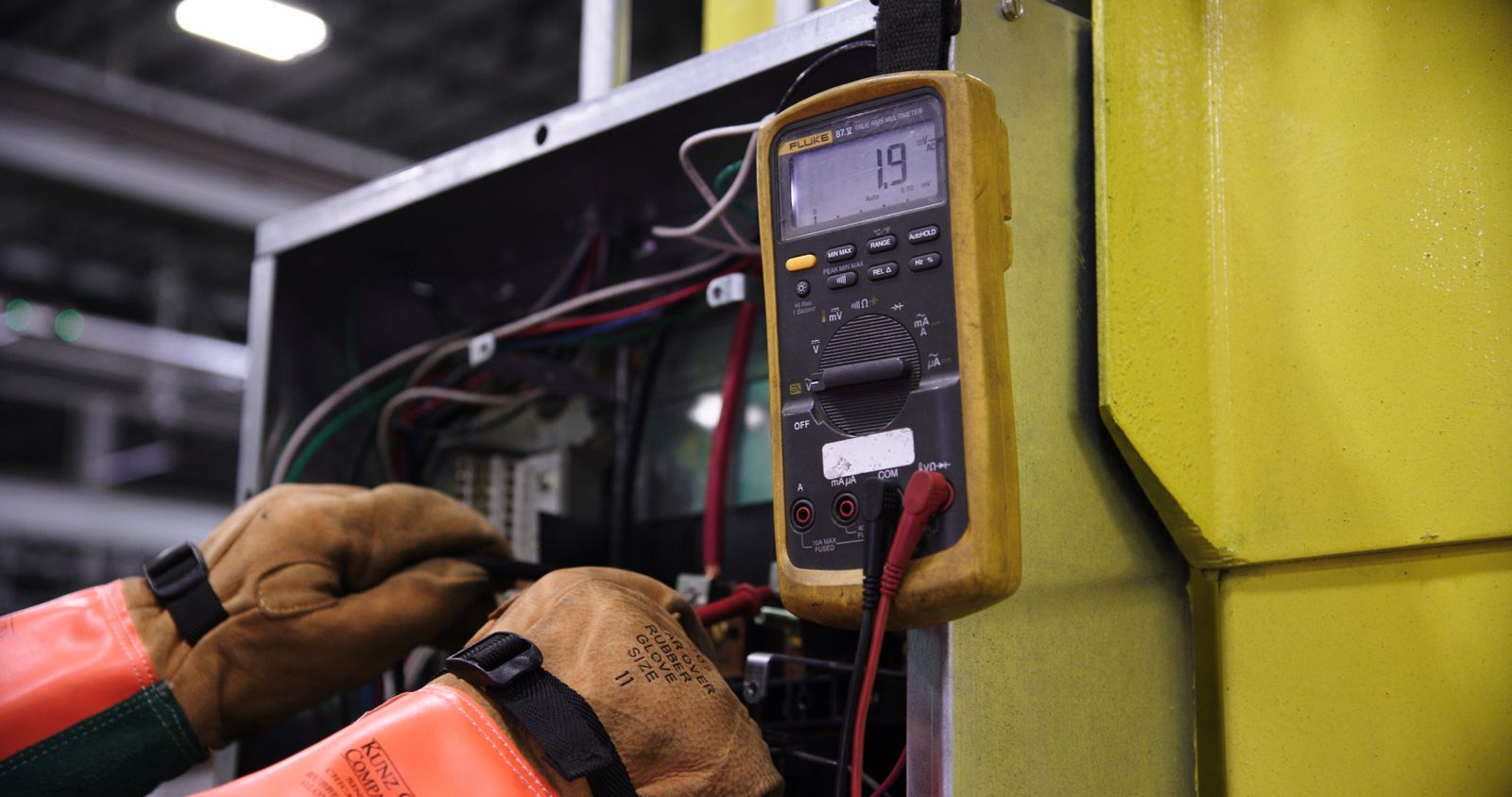 Messung an einer elektrischen Anlage mit Multimeter und Schutzhandschuhen