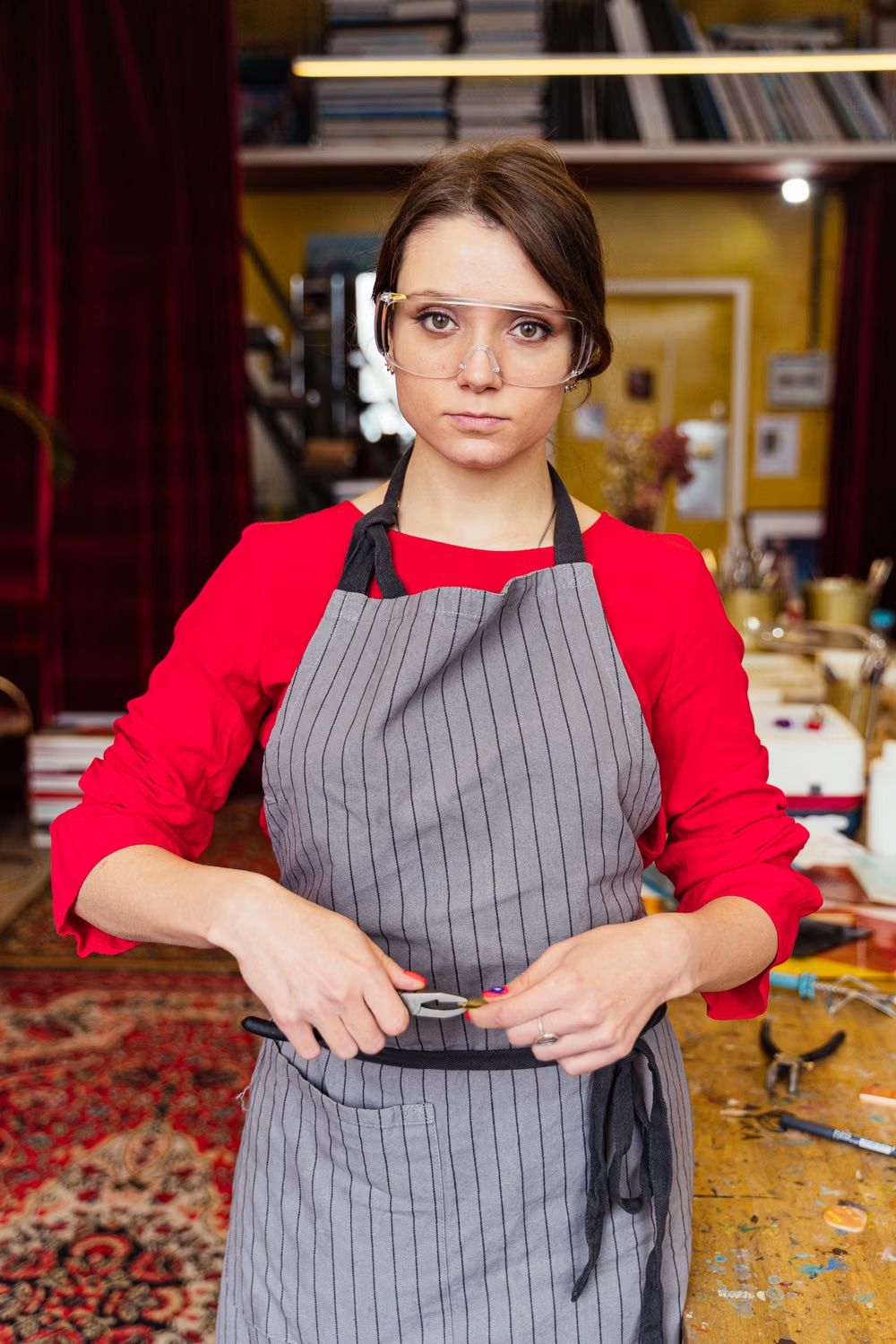Stockfoto: Frau mit Schutzbrille und Werkzeug in einer Werkstatt