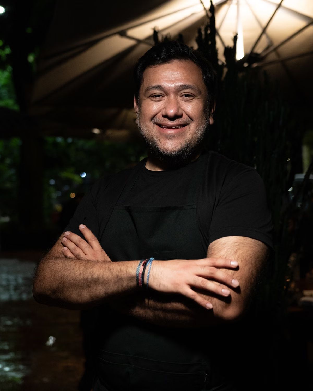 Stockfoto: Lächelnder Mann mit schwarzer Schürze vor einem Restaurant