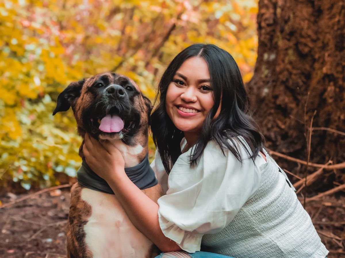 Stockfoto: Lächelnde Frau mit einem Hund im Freien